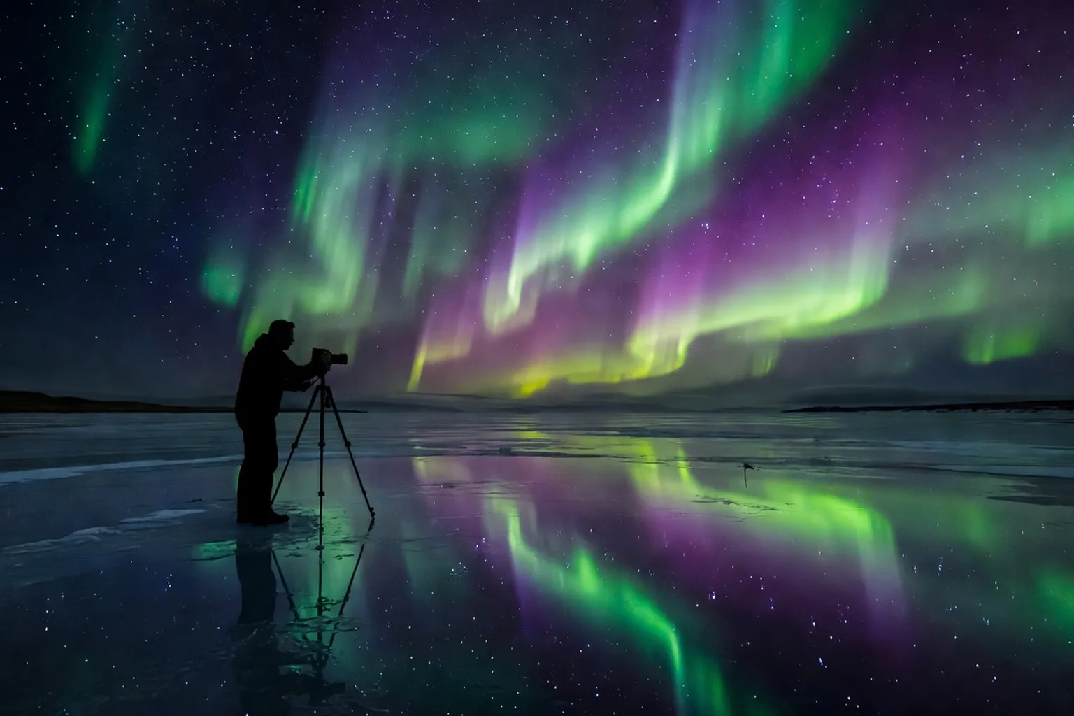 Photographe avec trépied sur lac gelé en Islande sous les aurores boréales