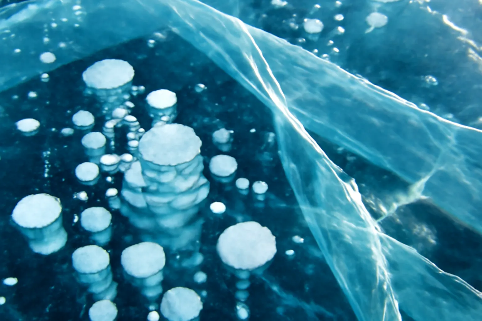 Glace turquoise transparente du lac Baikal avec fissures en hiver